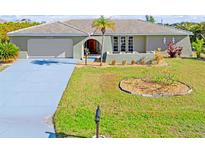 Single-story home with a large driveway and well-manicured lawn at 138 Peckham Sw St, Port Charlotte, FL 33952