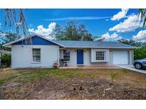 Front yard view of a charming house with a blue door and attached garage at 4485 Herder St, Port Charlotte, FL 33948