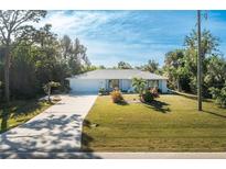 Single story home with light paint, landscaping, and driveway at 18565 Edgewater Dr, Port Charlotte, FL 33948