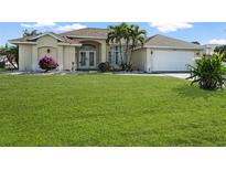 Single-story home with a lush lawn, double doors, and attached garage at 221 Sportsman Rd, Rotonda West, FL 33947