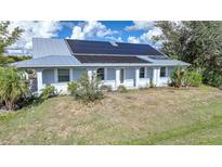 Single-story home with metal roof and solar panels, showcasing curb appeal at 4132 Michel Tree St, Port Charlotte, FL 33948