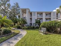 Paved walkway leading to a building with green lawn and a bench at 437 Cerromar Ln # 312, Venice, FL 34293