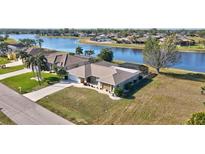 Waterfront home with a well-manicured lawn, mature palm trees, and a screened lanai overlooking the scenic water view at 2321 Sofia Ln, Punta Gorda, FL 33983