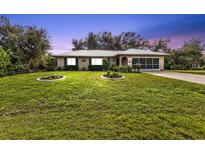 Single story home with a well-manicured lawn and metal roof at 22481 Vale Ave, Punta Gorda, FL 33980