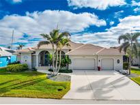 Single-Gathering home with three-car garage, palm trees, and landscaped lawn at 3406 Saint Croix Ct, Punta Gorda, FL 33950