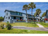 Coastal townhome showcasing blue exterior, manicured lawn, palm trees, and walkway on a sunny day at 1839 Settlers Dr # B-6, Nokomis, FL 34275