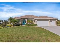 Single-story home with three-car garage, teal front door, and manicured lawn at 45 Marker Rd, Rotonda West, FL 33947