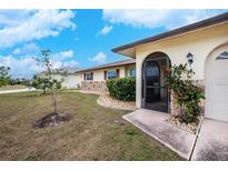 House exterior featuring a landscaped yard and screened entryway at 109 Peckham Se St, Port Charlotte, FL 33952