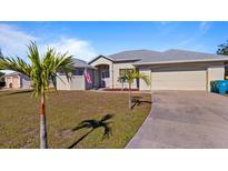 Well-maintained house featuring a two-car garage and lush landscaping at 17220 Horizon Ln, Port Charlotte, FL 33948