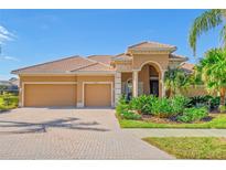 Tan two-story house with a three-car garage and lush landscaping at 1906 Creek Nine Dr, North Port, FL 34291