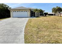 Single-story home with a large driveway and spacious front yard at 2057 Wonderwin St, Port Charlotte, FL 33948