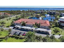 Aerial view of condo complex showcasing lake, parking, and building at 23465 Harborview Rd # 1006, Punta Gorda, FL 33980