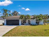 White house with black garage door, palm trees, and a well-manicured lawn at 2418 Frantz St, North Port, FL 34286