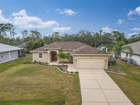 Tan one-story house with a red door and landscaped yard at 4557 Sabrina Ter, North Port, FL 34286