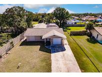 Aerial view of a single-story house with a large backyard and driveway at 701 Coral Way, Englewood, FL 34223