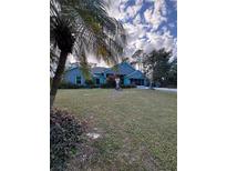 Gray house with teal accents, lush lawn, and palm trees at 1281 Nebraska Ln, North Port, FL 34286