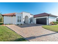 White stucco home with red tile roof, arched entryway, and paver driveway at 25606 Aysen Dr, Punta Gorda, FL 33983