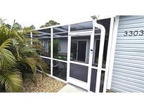 White-framed screened patio entrance with gray siding and landscaping at 3300 Loveland Blvd # 3303, Punta Gorda, FL 33980