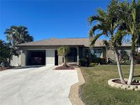 Single-story home with a two-car garage and landscaped yard at 3761 Peace River Dr, Punta Gorda, FL 33983