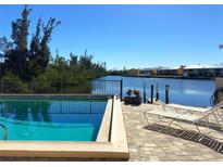 Community pool with canal view and lounge chairs at 1217 Aqui Esta Dr # 5, Punta Gorda, FL 33950