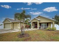 Tan house with 3-car garage, palm trees, and a covered entryway at 13536 Ainsworth Ln, Port Charlotte, FL 33981