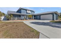 Charming blue home with a white garage door and a well-manicured lawn at 18500 Ohara Dr, Port Charlotte, FL 33948