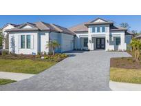 Two-story home with a gray tile roof, white walls, and a paver driveway at 10628 Nicklaus Ct, Englewood, FL 34223