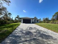 White house with gray paver driveway and dark garage door at 12547 Trinity Ave, Port Charlotte, FL 33953