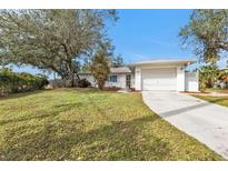 White single-story home with attached garage and manicured lawn at 21190 Midway Blvd, Port Charlotte, FL 33952