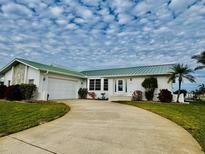 Single-story home with a green metal roof, attached garage, and landscaped yard at 2218 Cassino Ct, Punta Gorda, FL 33950