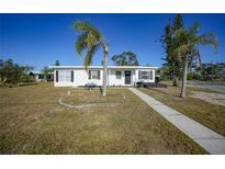 White single story home with palm trees and landscaped lawn at 230 Waterway Ne Cir, Port Charlotte, FL 33952