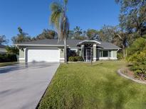 Charming single-story home with well-manicured lawn, mature trees, and a two-car garage at 3341 Briant St, North Port, FL 34287