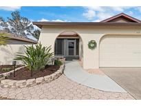 Inviting exterior with landscaped walkway leading to a covered entryway and attached garage at 616 Cherrywood Dr, Englewood, FL 34223