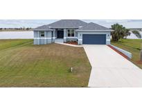 One-story home with gray siding, attached garage, and landscaped yard at 27 Meadowlark Ln, Placida, FL 33946