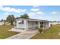 White single-wide mobile home with carport and landscaped yard at 6305 Parkview Ct, North Port, FL 34287