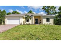 Single-story home with a white garage door and a neatly landscaped lawn at 14386 San Domingo Blvd, Port Charlotte, FL 33981