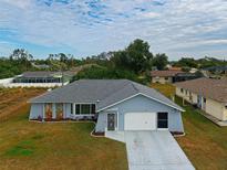 Single-story home with gray roof, white garage door, and landscaped yard at 2798 Rock Creek Dr, Port Charlotte, FL 33948