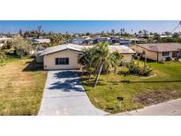 Aerial view of a single Gathering home with driveway and green lawn at 3200 Colony Ct, Punta Gorda, FL 33950