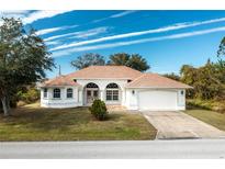 Single-story home with a two-car garage and attractive landscaping at 437 Loveland Blvd, Port Charlotte, FL 33954