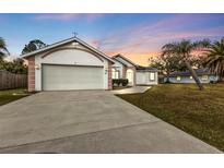 House exterior at sunset, featuring a two-car garage and manicured lawn at 87 Torrington St, Port Charlotte, FL 33954