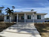 Modern single story home with gray and white exterior, landscaping, and concrete stairs at 1209 Nordendale Blvd, North Port, FL 34288