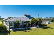 Gray metal roof house with lush landscaping, large driveway and detached garage at 2329 Pinellas Dr, Punta Gorda, FL 33983
