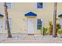 Exterior view of a light yellow building with a blue awning and white door at 26346 Rampart Blvd # 904, Punta Gorda, FL 33983
