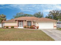 Tan house with brown roof, white garage door, and landscaped yard at 4046 Lubec Ave, North Port, FL 34287