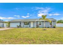Newly renovated home with gray exterior, white garage door, and landscaped lawn at 745 Kellstadt Nw St, Port Charlotte, FL 33952