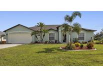 One-story home with a green exterior, a large yard, and palm trees at 1188 Paraclete Rd, Punta Gorda, FL 33983