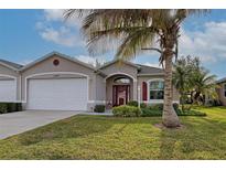 Tan house with white garage door, red door, and palm tree in front at 1347 Hedgewood Cir, North Port, FL 34288