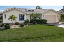 White one-story home with blue door, landscaping, and a two-car garage at 1511 Casey Key Dr, Punta Gorda, FL 33950