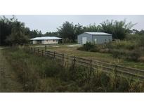 Aerial view of a house and detached garage on a large lot with fenced area at 15570 Rasmussen Rd, Punta Gorda, FL 33982