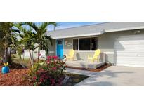 Brightly colored home exterior, featuring a manicured lawn, and a welcoming front porch at 18086 Clanton Ave, Port Charlotte, FL 33948